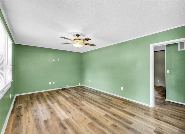 1045 Briarcliff Dr, Rantoul, IL 61866 - spare room featuring a textured ceiling, ceiling fan, wood finished floors, baseboards, and crown molding