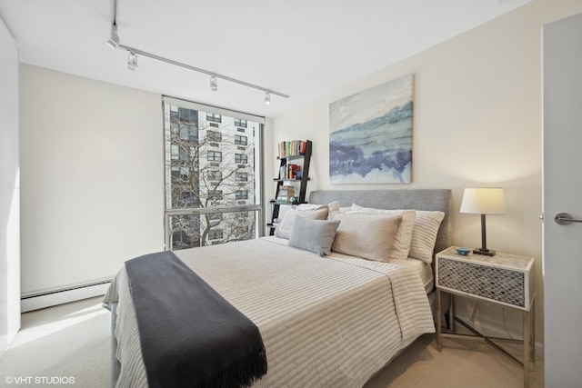 bedroom with a baseboard radiator, carpet floors, and rail lighting