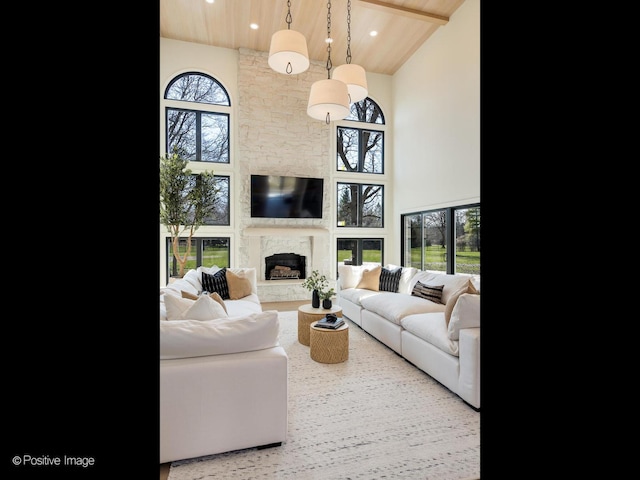 living area with a stone fireplace, wood ceiling, and high vaulted ceiling