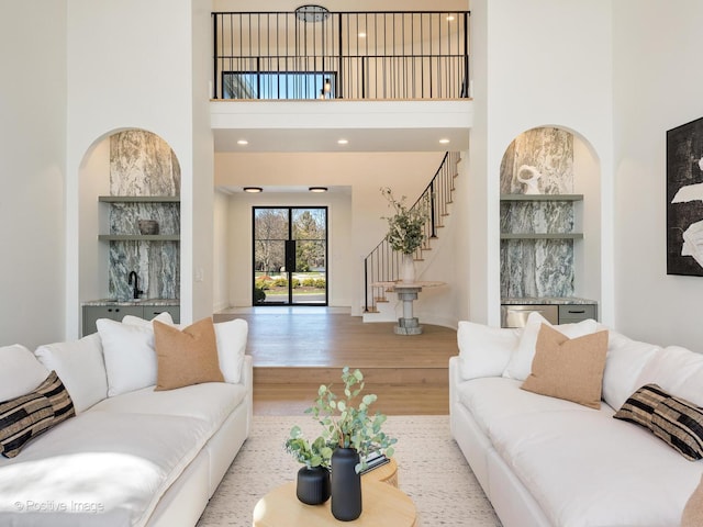living room featuring a towering ceiling, baseboards, wood finished floors, and stairs