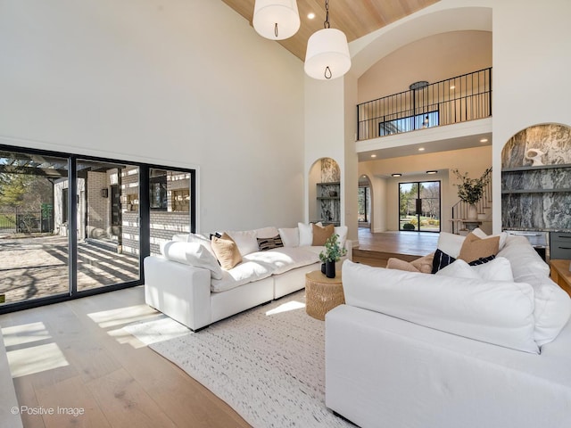 living room with high vaulted ceiling, arched walkways, hardwood / wood-style flooring, and wooden ceiling