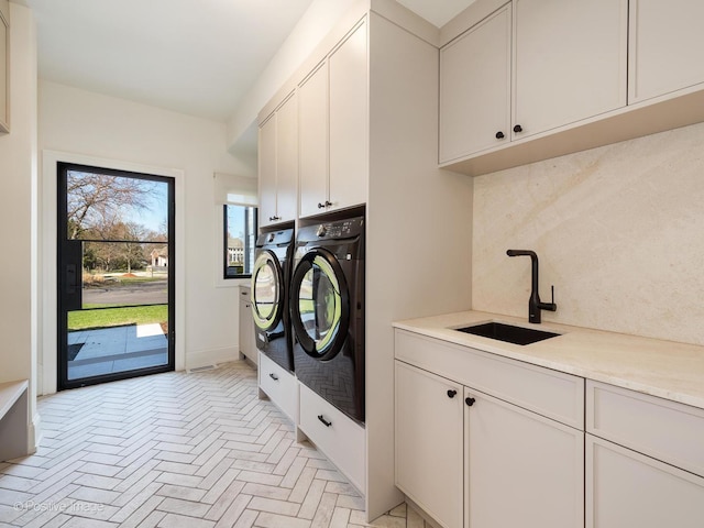 clothes washing area with washer and clothes dryer, cabinet space, a sink, and brick floor
