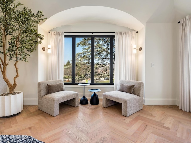 sitting room featuring arched walkways and baseboards