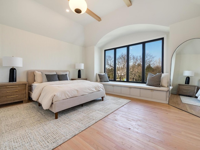bedroom with light wood-style floors and beam ceiling