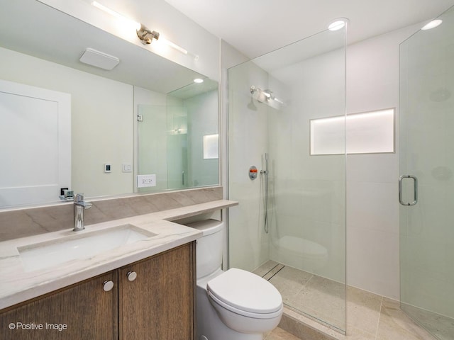 bathroom featuring vanity, a shower with door, and toilet