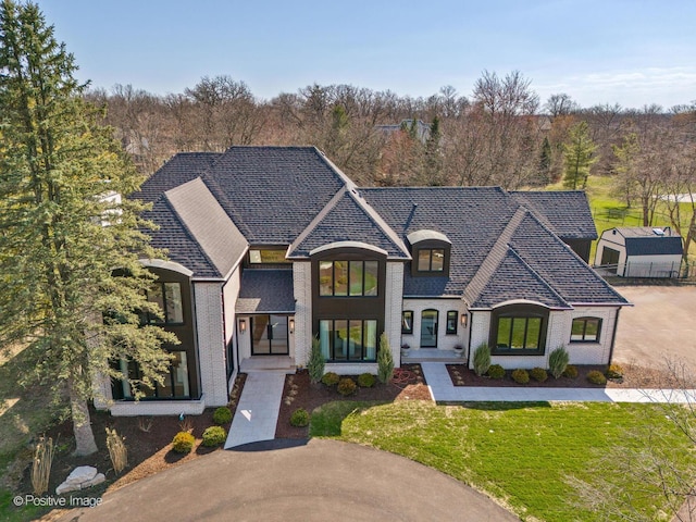 french provincial home featuring brick siding and a front yard