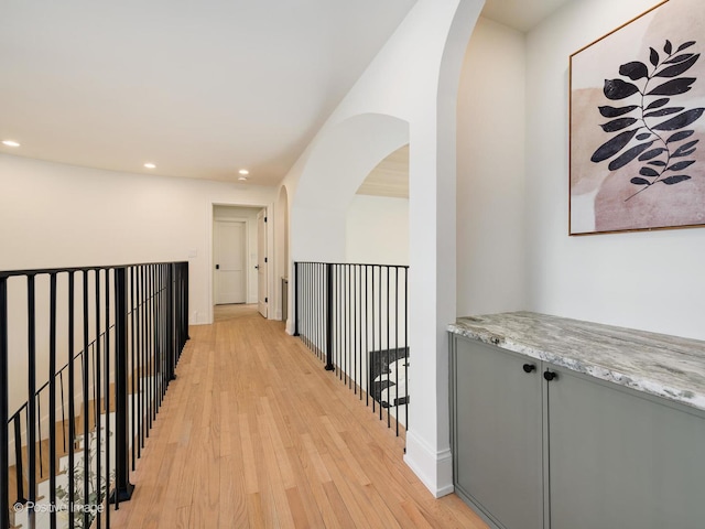 corridor with arched walkways, recessed lighting, and light wood-type flooring