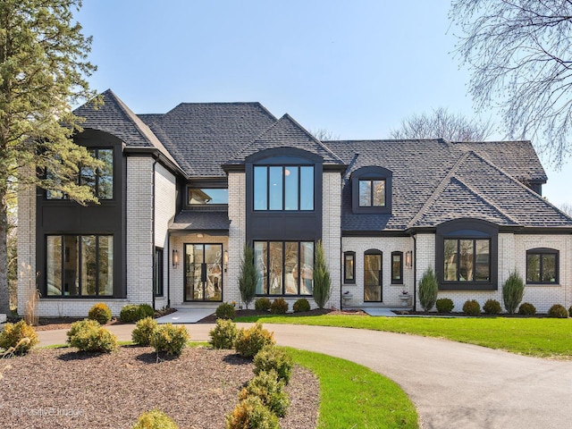 french provincial home featuring brick siding and a front yard