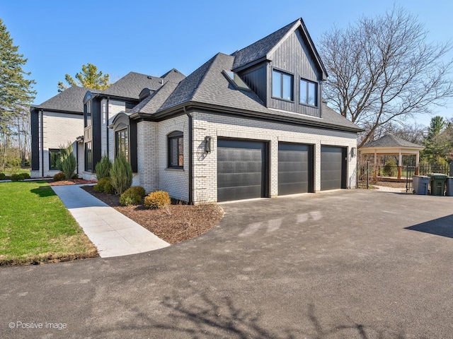 view of front of property with an attached garage, aphalt driveway, a front lawn, and brick siding