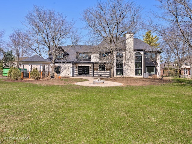 rear view of house featuring a lawn and an outdoor fire pit