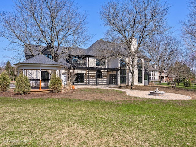 rear view of property with a gazebo, a lawn, and an outdoor fire pit
