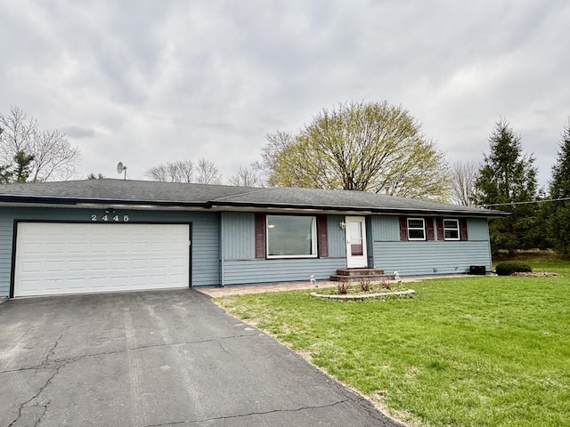 ranch-style home with an attached garage, a front lawn, and aphalt driveway