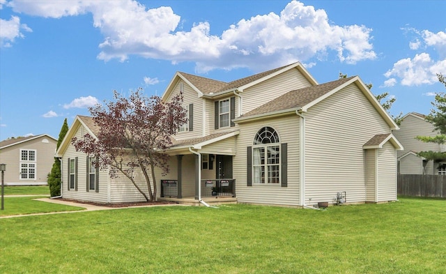 rear view of property featuring roof with shingles, fence, a yard, and a porch