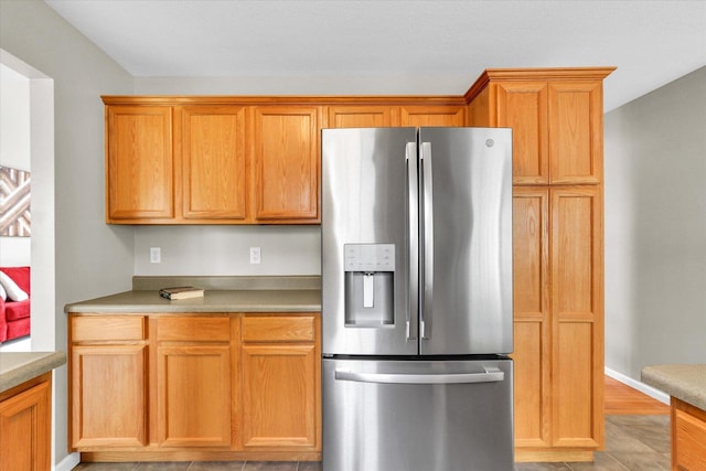 kitchen with light countertops, stainless steel fridge with ice dispenser, and light wood-type flooring