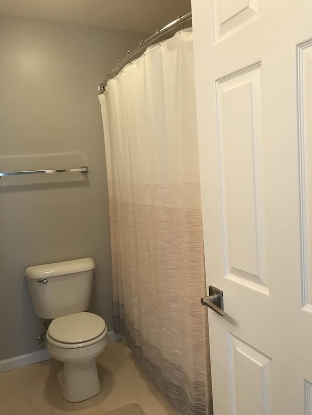 bathroom with baseboards, tile patterned flooring, curtained shower, and toilet
