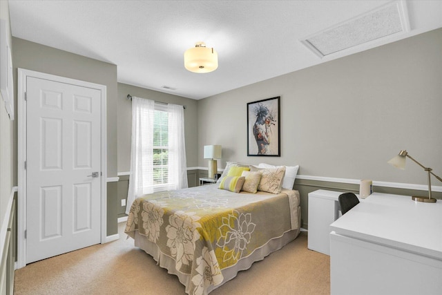 bedroom with visible vents, light colored carpet, and attic access