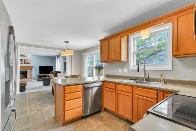 kitchen with appliances with stainless steel finishes, a sink, a peninsula, open floor plan, and pendant lighting
