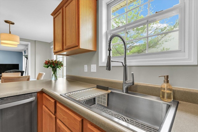 kitchen with a sink, hanging light fixtures, stainless steel dishwasher, and brown cabinets