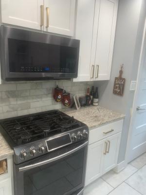 kitchen with light stone counters, stainless steel appliances, light tile patterned flooring, tasteful backsplash, and white cabinetry