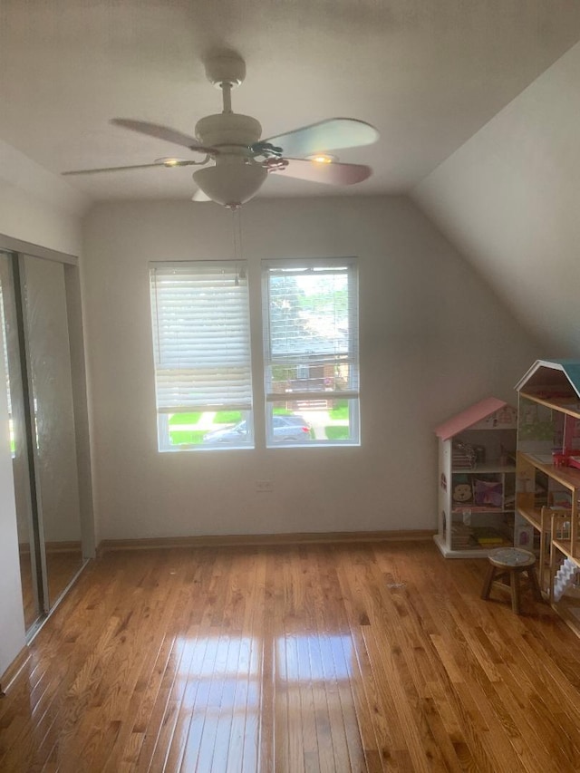 unfurnished bedroom with wood-type flooring, lofted ceiling, a closet, and a ceiling fan
