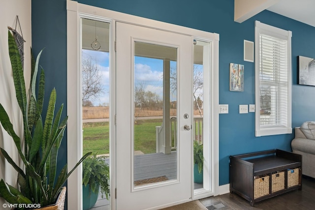 doorway to outside with dark wood finished floors, baseboards, and visible vents