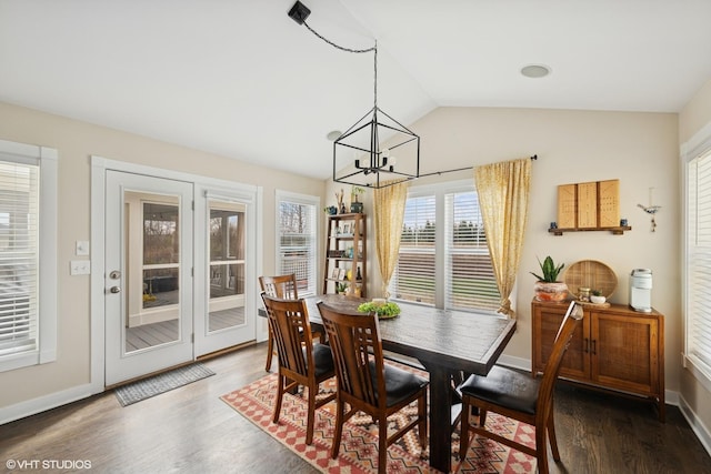 dining space with vaulted ceiling, wood finished floors, baseboards, and a notable chandelier