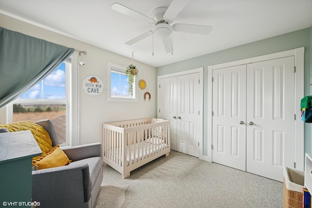bedroom with a nursery area, carpet floors, multiple closets, and ceiling fan