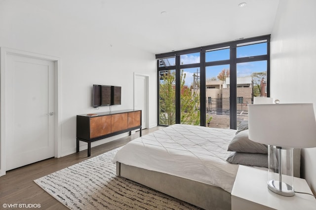 bedroom with baseboards, a wall of windows, and wood finished floors