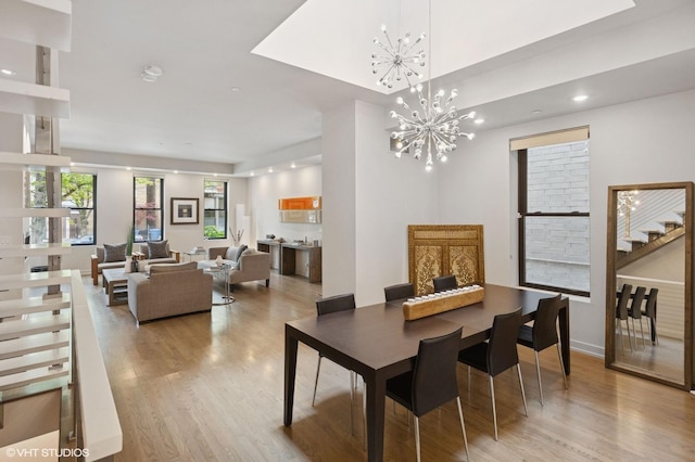 dining space with stairway, light wood finished floors, an inviting chandelier, and recessed lighting