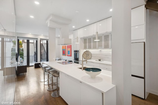 kitchen with white cabinets, stainless steel double oven, dark wood-style flooring, and modern cabinets