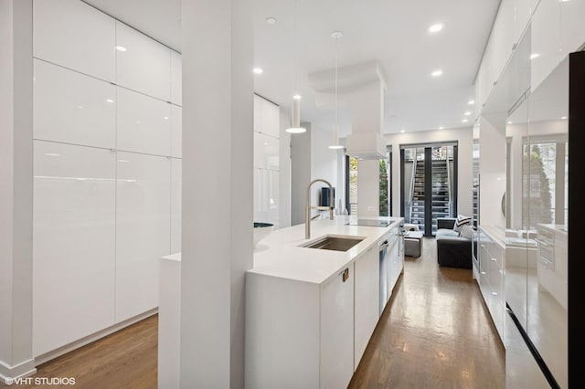 kitchen featuring modern cabinets, white cabinets, light wood-type flooring, and a sink