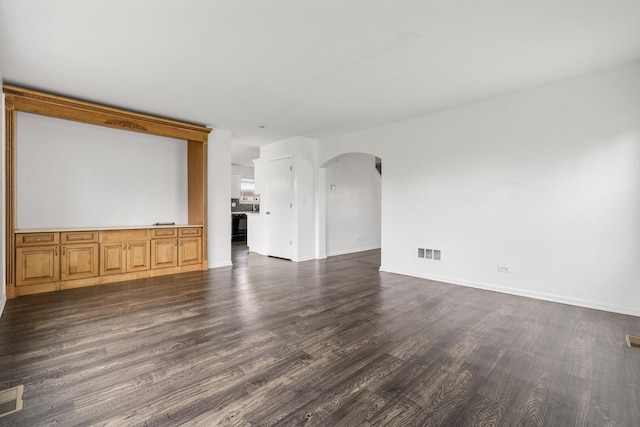 169 Waterbury Cir, Oswego, IL 60543 - unfurnished living room with baseboards, visible vents, arched walkways, and dark wood-type flooring