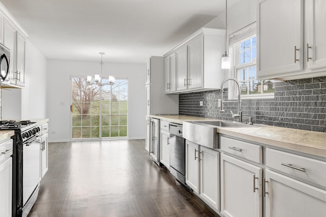 169 Waterbury Cir, Oswego, IL 60543 - kitchen with dark wood-style floors, dishwasher, gas range oven, decorative backsplash, and a chandelier