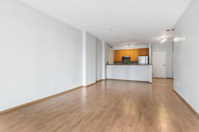unfurnished living room with light wood-style floors, baseboards, and track lighting