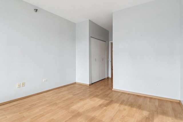 spare room featuring baseboards and light wood-type flooring