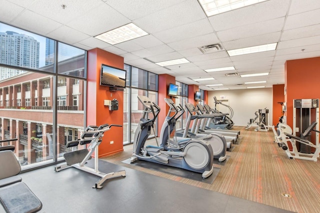 workout area with floor to ceiling windows, a paneled ceiling, and visible vents