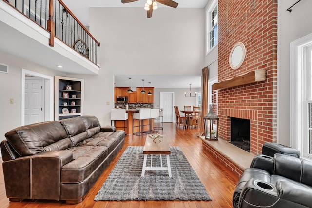 5255 Crescent Green Ct, Morris, IL 60450 - living room with a brick fireplace, hardwood / wood-style floors, a high ceiling, and ceiling fan