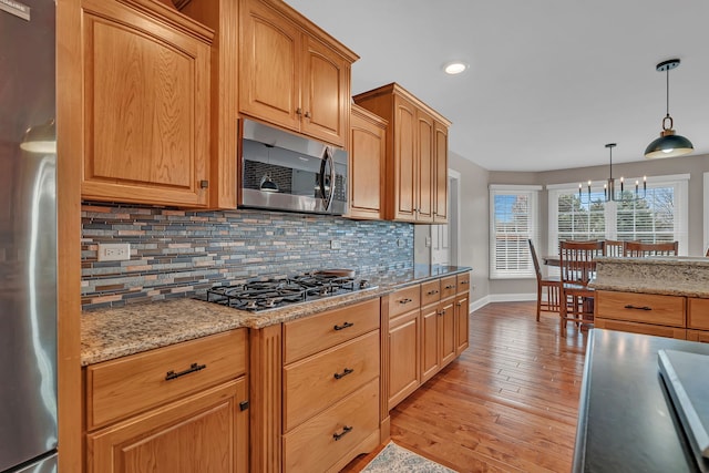 5255 Crescent Green Ct, Morris, IL 60450 - kitchen with light stone counters, decorative backsplash, light wood finished floors, baseboards, and appliances with stainless steel finishes