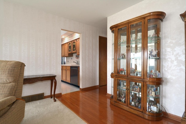 corridor with baseboards, visible vents, wallpapered walls, and light wood-type flooring