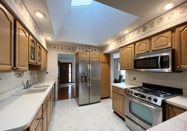 kitchen with light countertops, appliances with stainless steel finishes, decorative backsplash, and a sink