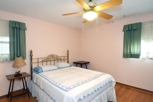 bedroom with wood finished floors, a ceiling fan, and baseboards