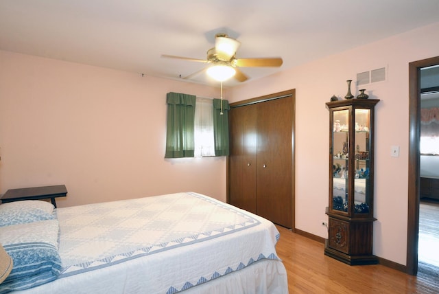 bedroom featuring baseboards, visible vents, a ceiling fan, wood finished floors, and a closet
