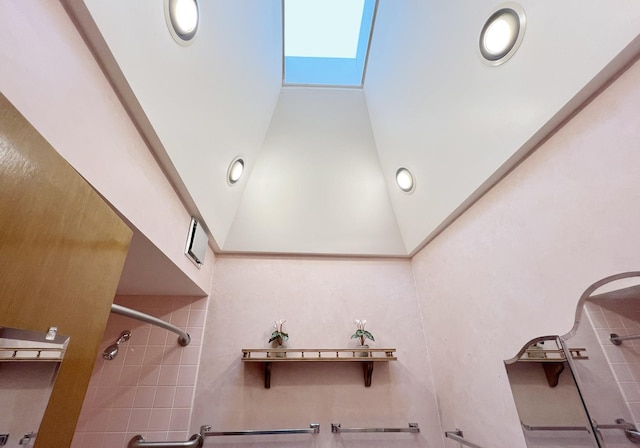 full bath featuring a high ceiling, a shower, and a skylight