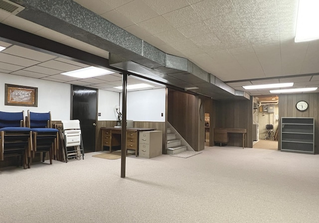 finished below grade area with wooden walls, visible vents, carpet, and stairs