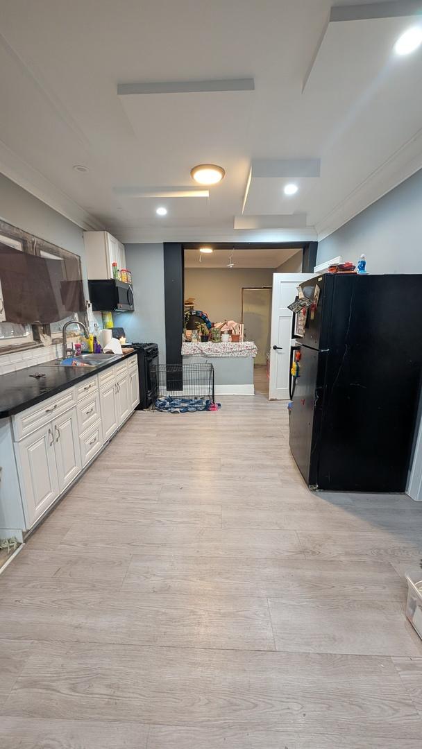 3039 W Flournoy St, Chicago, IL 60612 - kitchen featuring white cabinets, a sink, light wood-type flooring, dark countertops, and freestanding refrigerator