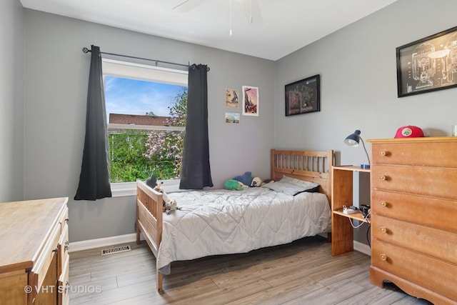 bedroom featuring light wood-style floors, a ceiling fan, baseboards, and visible vents