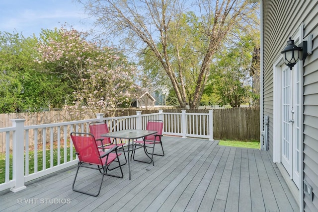 wooden terrace with outdoor dining area and a fenced backyard