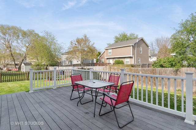 wooden terrace featuring a residential view, outdoor dining space, a yard, and a fenced backyard