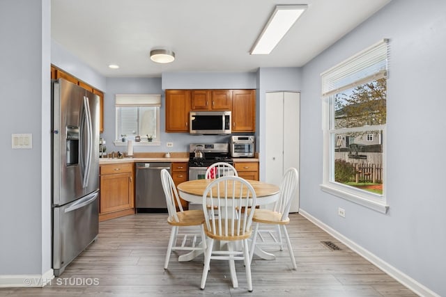 kitchen featuring visible vents, baseboards, light countertops, light wood finished floors, and stainless steel appliances