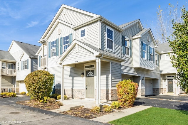 view of front facade with aphalt driveway, brick siding, and a garage
